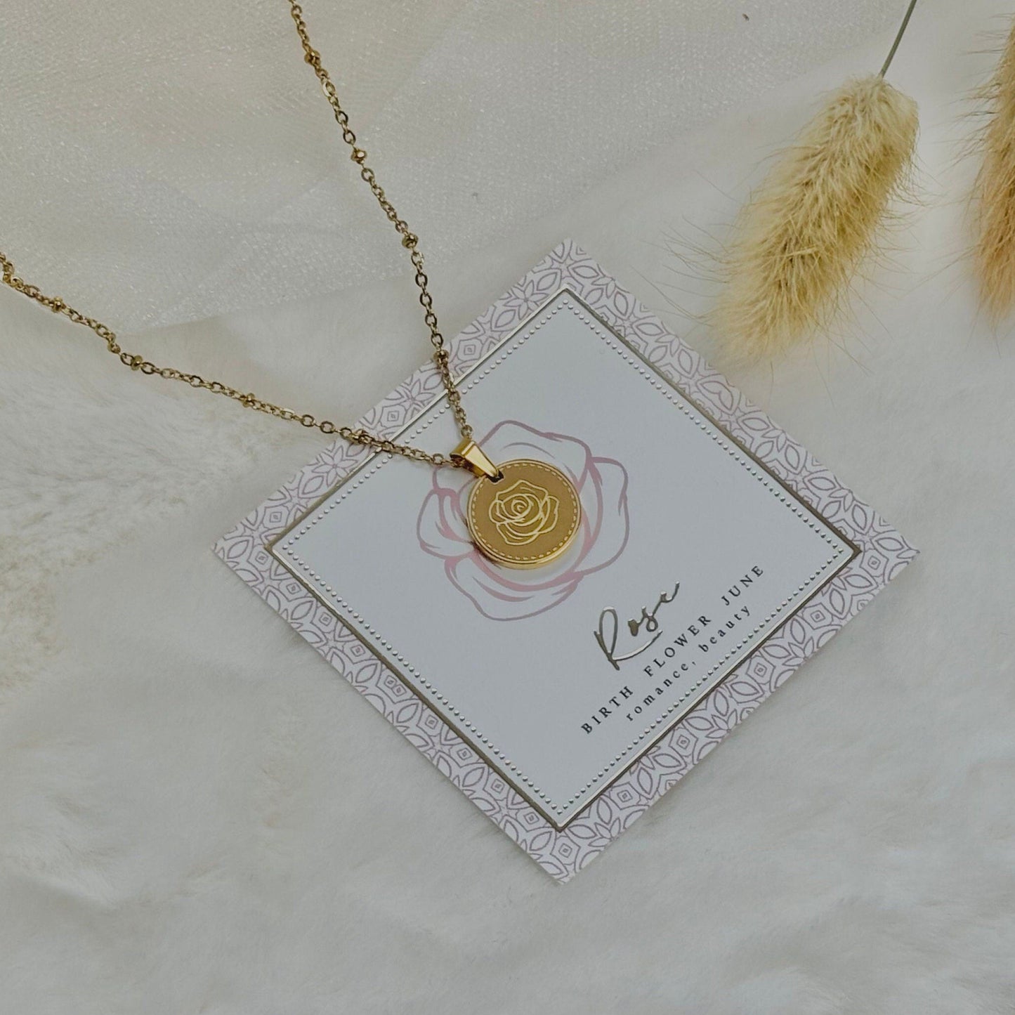 Gold necklace on a decorative card with a floral design, placed on a textured surface.