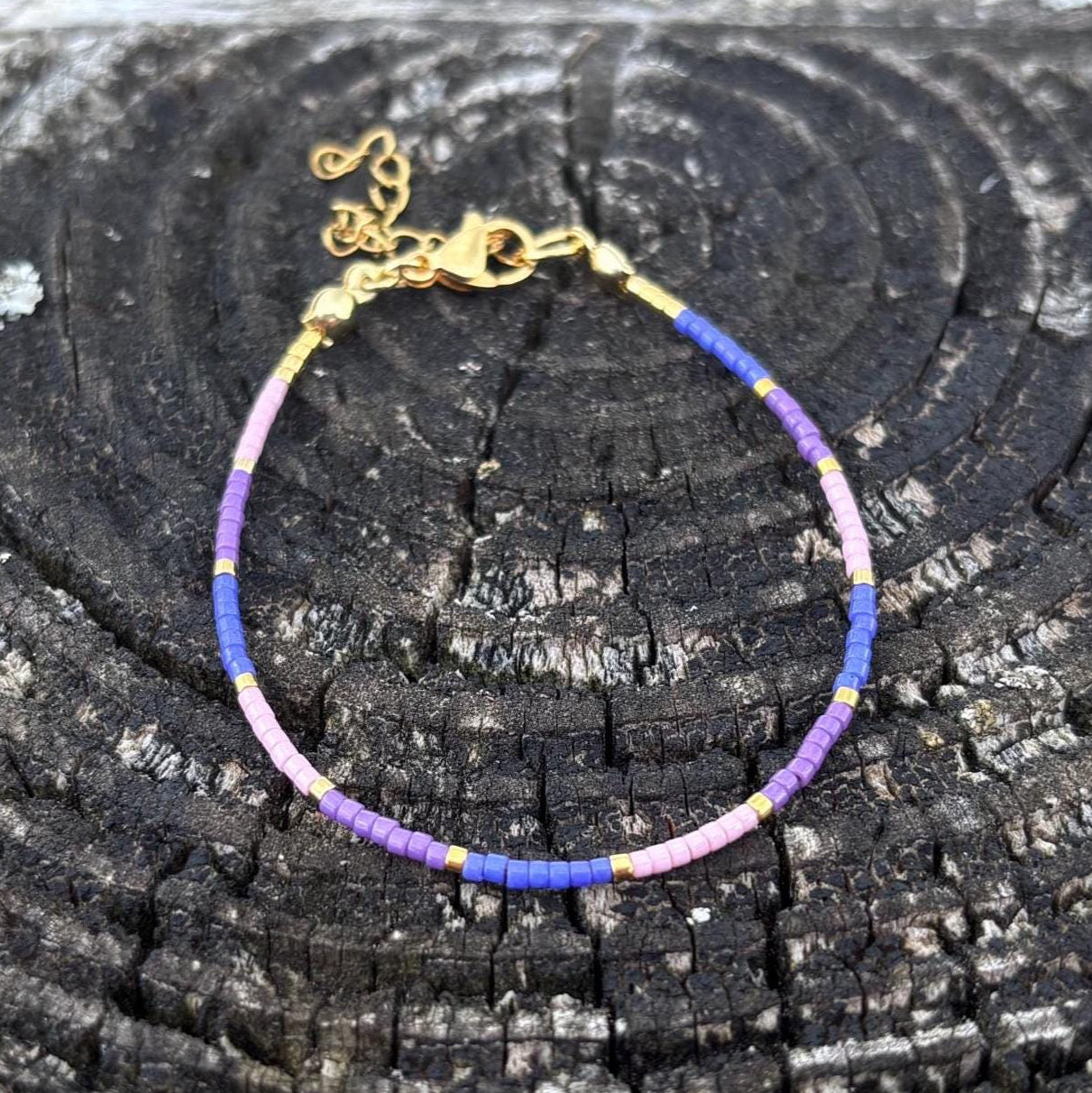 Bracelet with purple and pink beads on a textured black surface