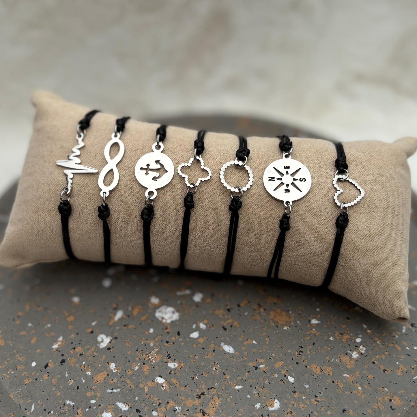 Set of silver bracelets with various charms on a beige pillow