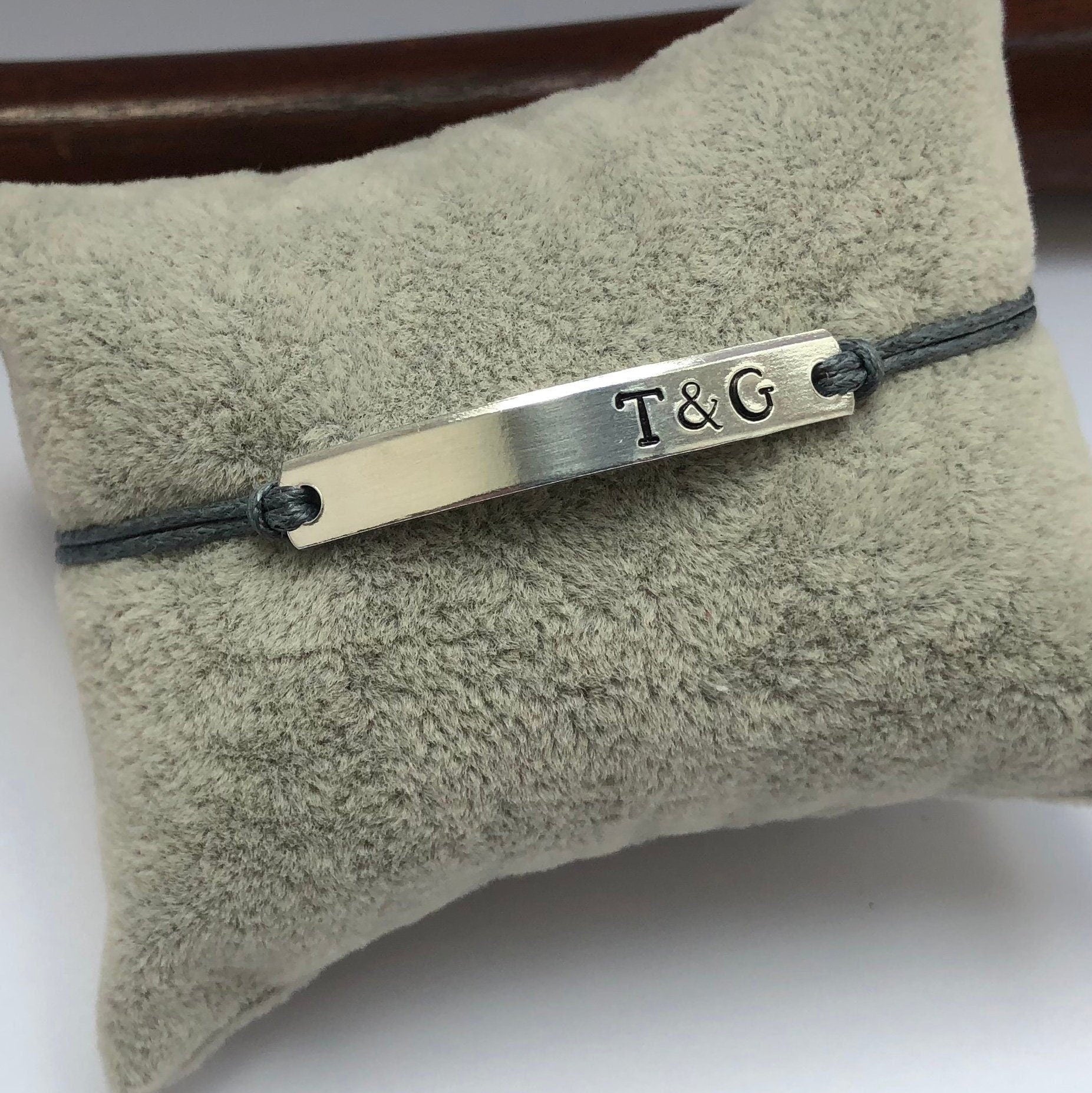 Silver bracelet with 'T&G' engraving on a soft fabric surface