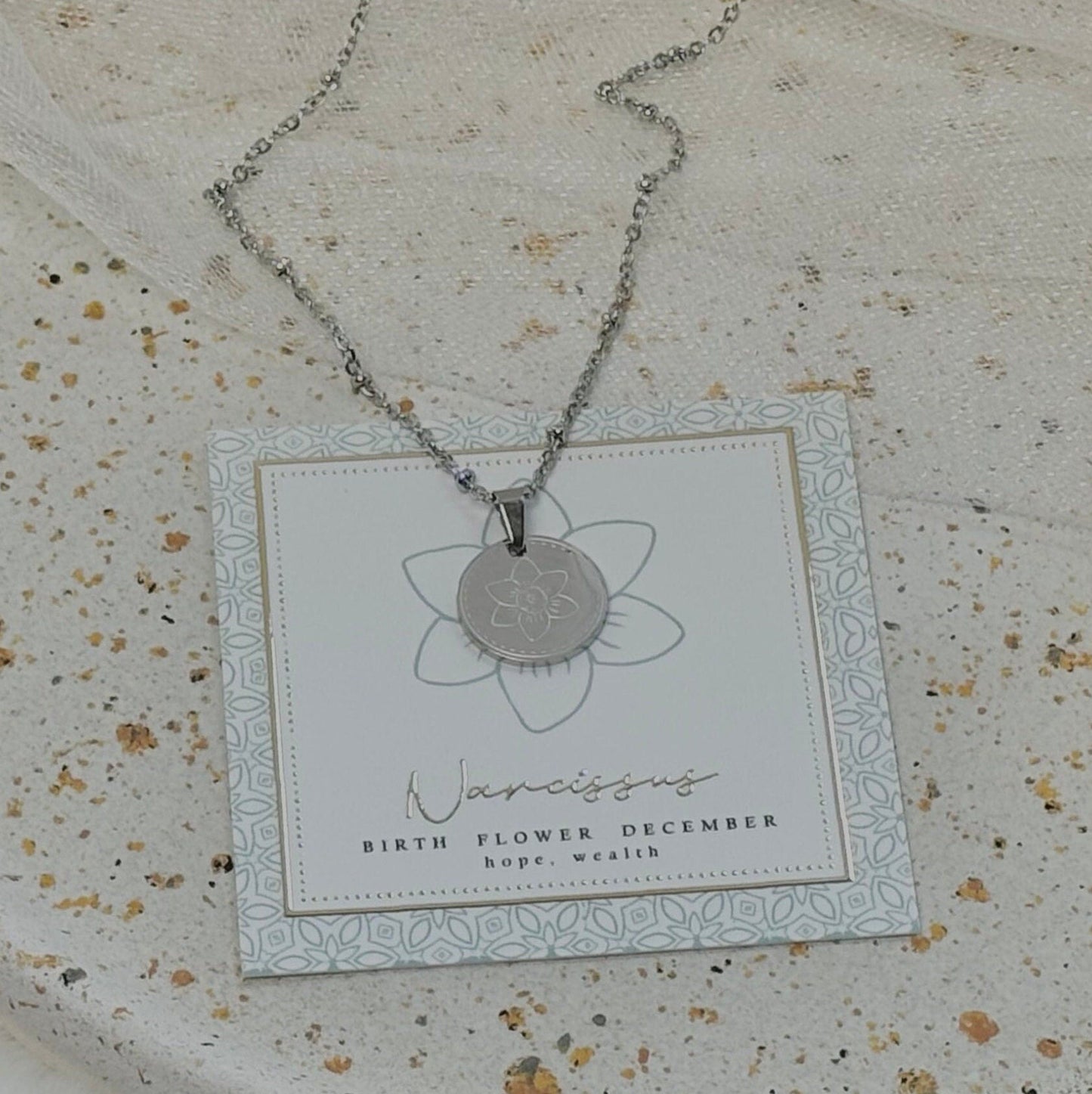 Necklace with a pendant on a branded card against a textured surface