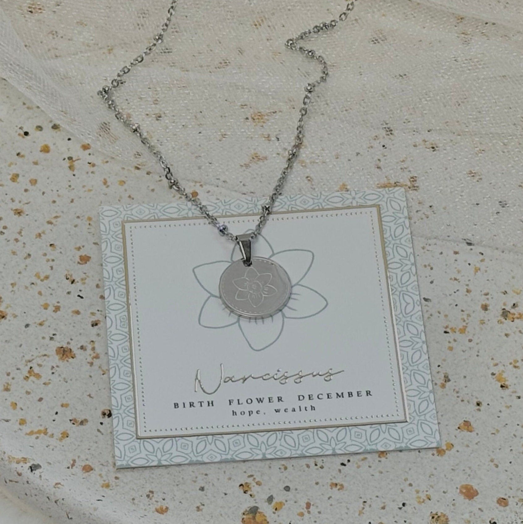 Necklace with a pendant on a branded card against a textured surface