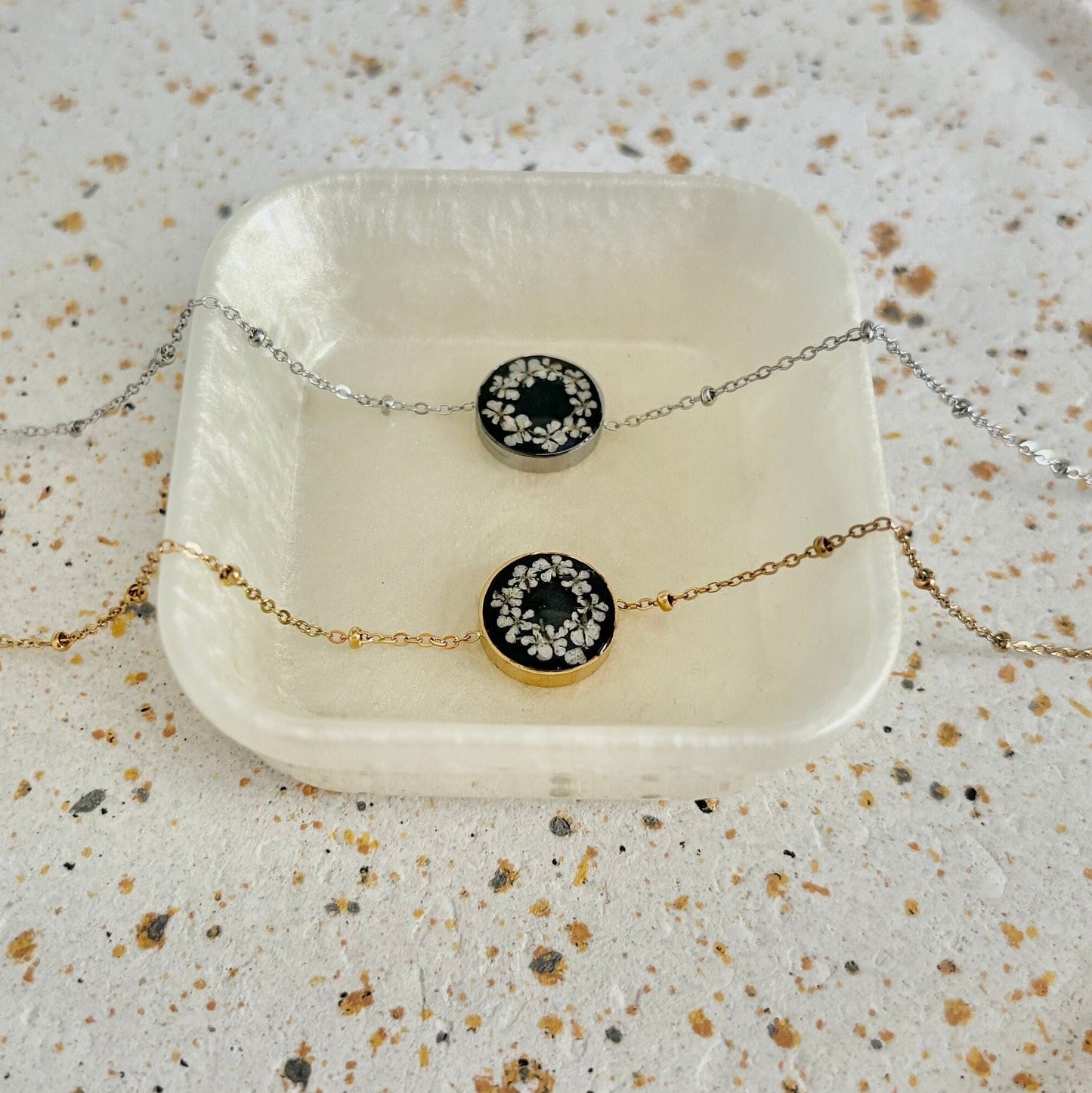 Necklace with black and gold circular pendant on a textured surface