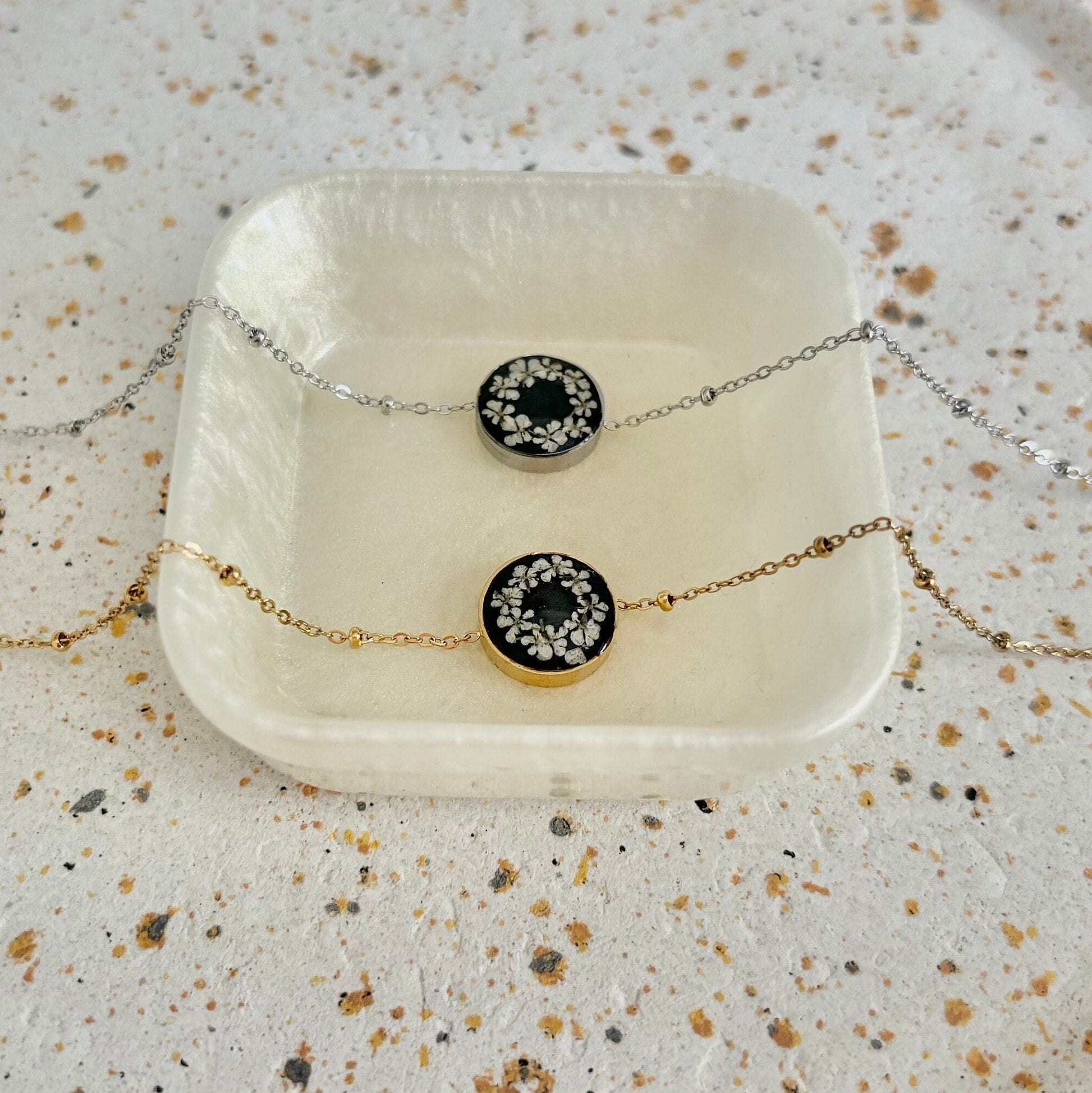 Necklace with black and gold circular pendant on a textured surface