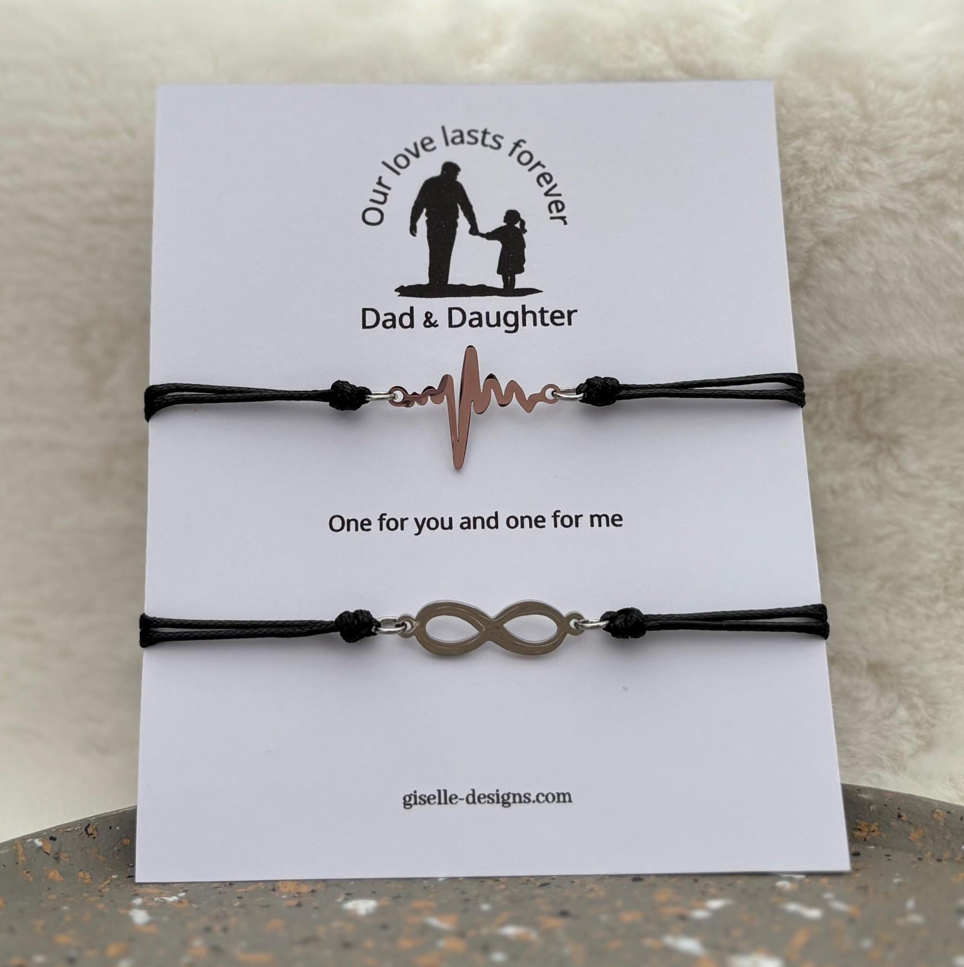 Two black bracelets with heart and infinity symbols on a card with 'Dad & Daughter' text.