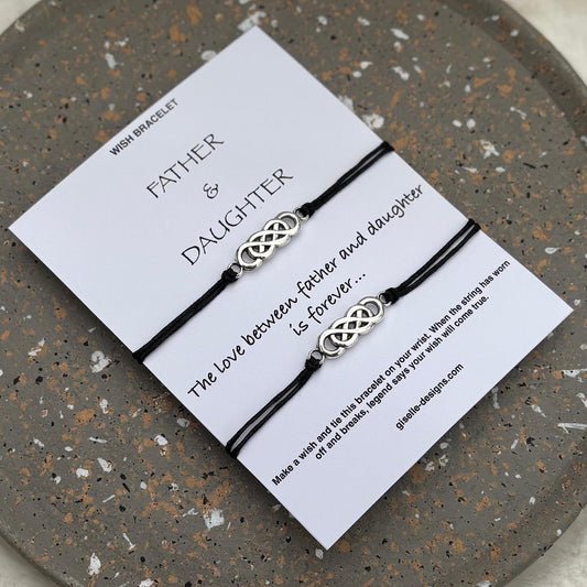 Two intertwined bracelets on a card with text on a speckled stone surface