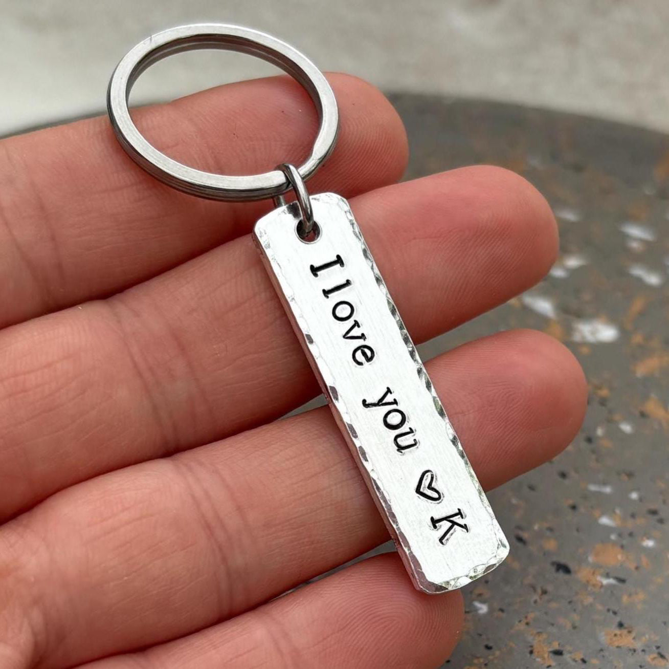 Silver keychain with 'I love you VK' engraving held in a hand.