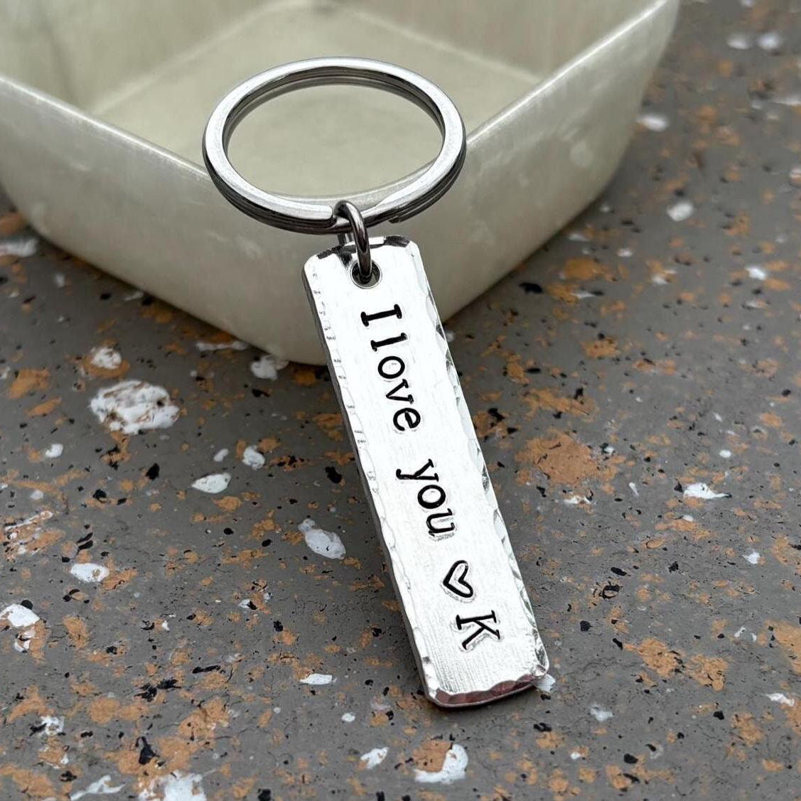 Silver keychain with 'I love you' tag on a textured surface