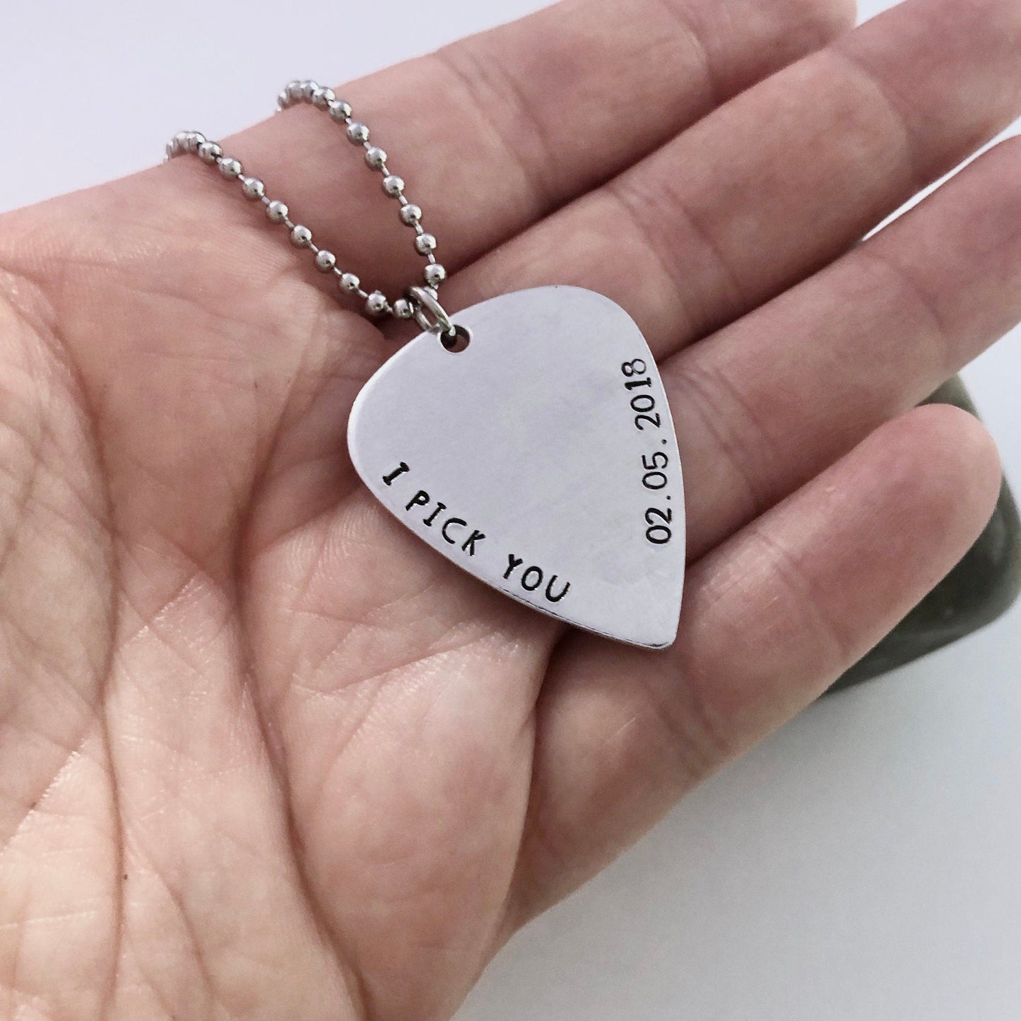 Heart-shaped pendant with 'I pick you' engraving on a hand
