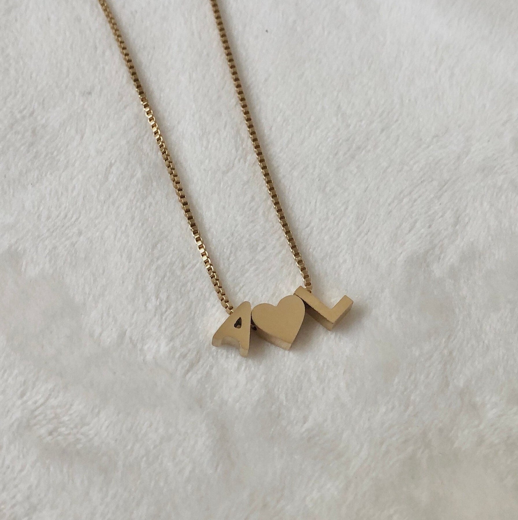 Gold necklace with '4L' pendant on a white background