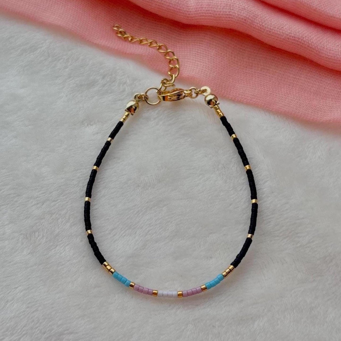 Bracelet with black and gold beads on a light gray background