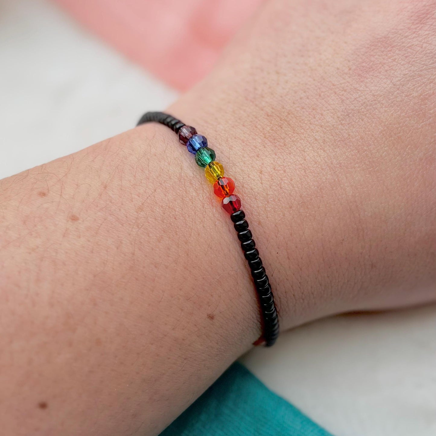 Rainbow beaded bracelet on a wrist with a blurred background