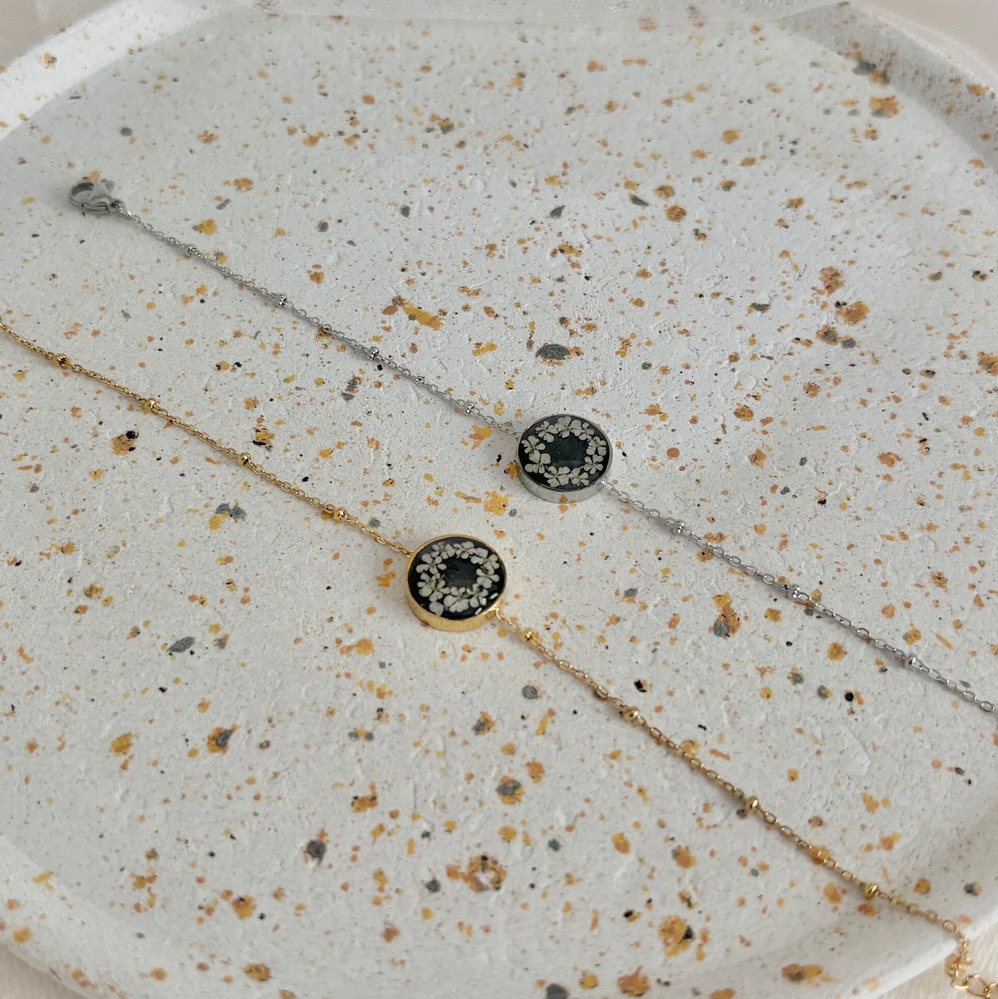 Necklace with black and gold beads on a speckled stone surface
