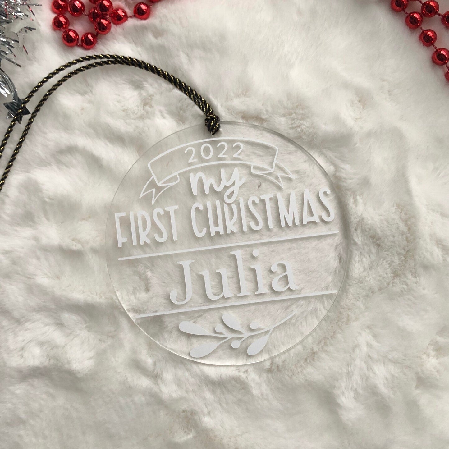Clear ornament with 'my first Christmas Julia' text on a snowy background