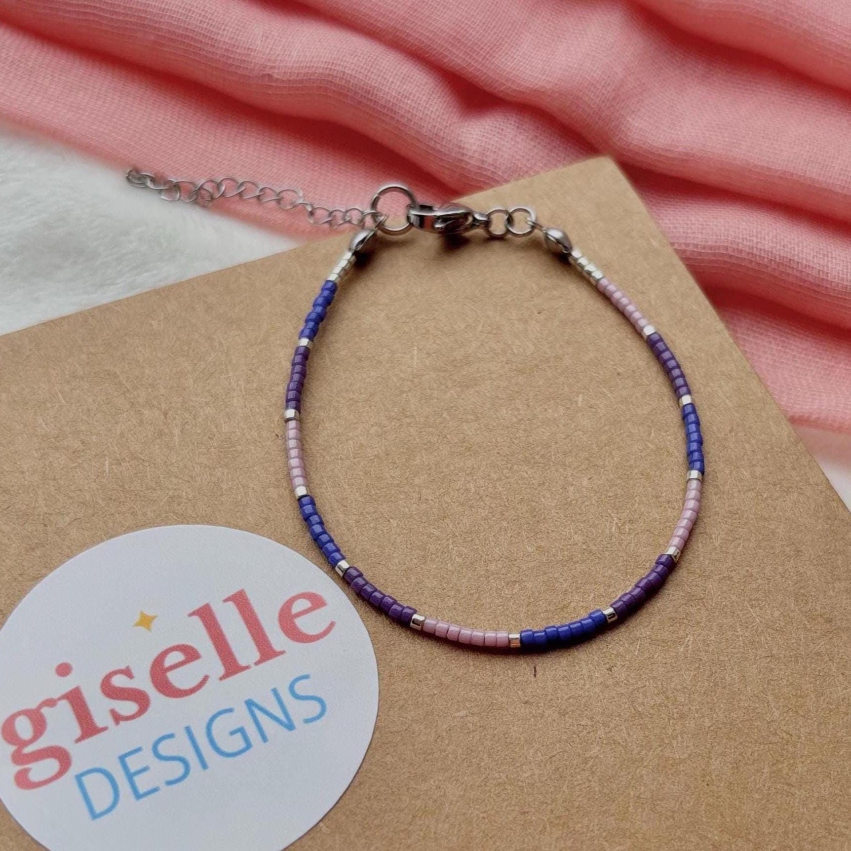 Bracelet with beaded design on a brown card with 'giselle DESIGNS' label, pink fabric in the background