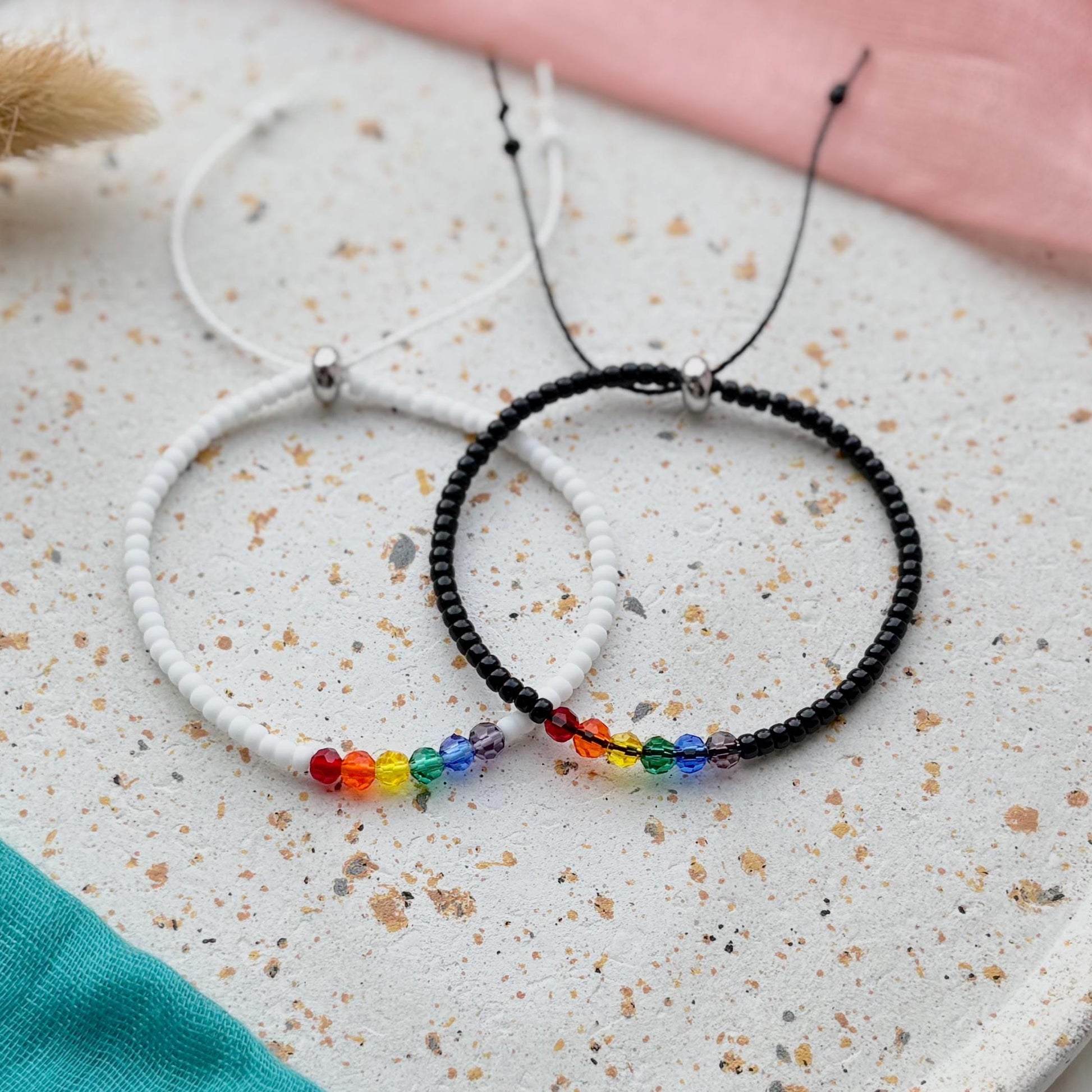 Two beaded necklaces on a textured surface with a colorful bead detail.