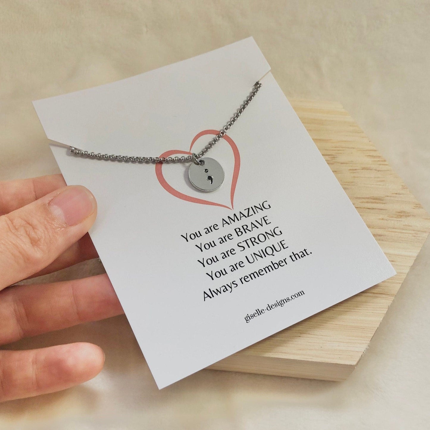 Necklace with a message card held by a hand on a wooden surface