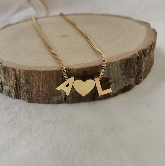 Gold necklace with heart and '4L' pendant on a wooden block