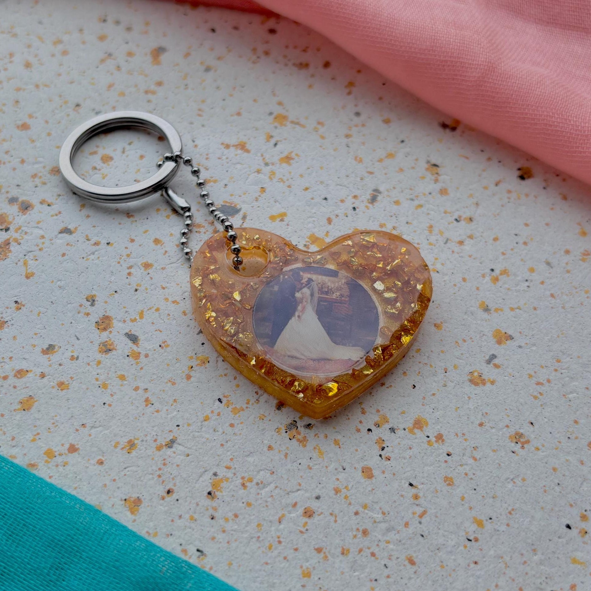 Heart-shaped keychain with a pendant on a speckled ceramic plate