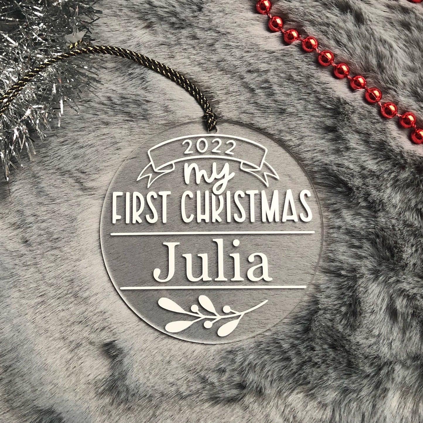 Decorative ornament for 'My First Christmas' with name 'Julia' on a textured surface.