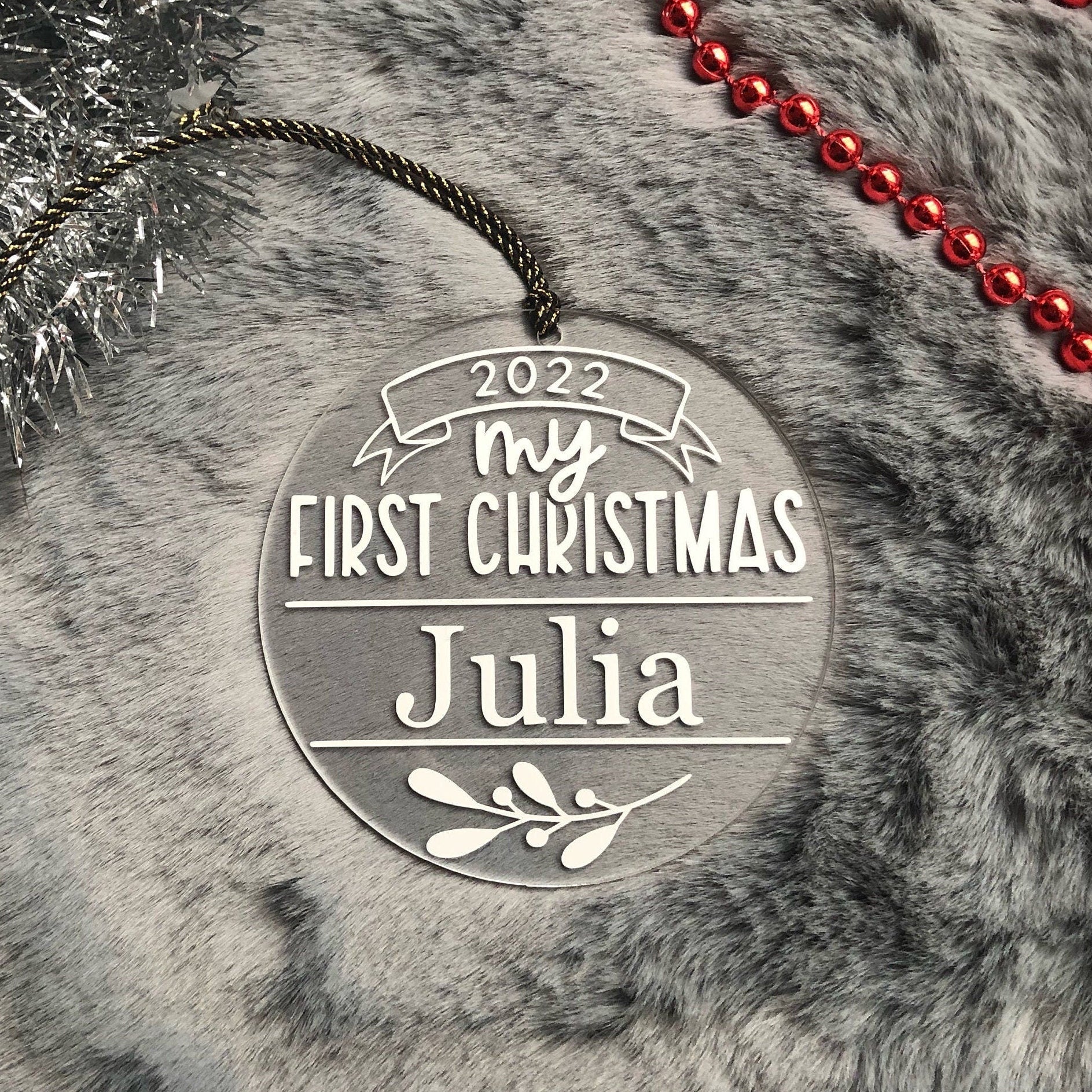 Decorative ornament for 'My First Christmas' with name 'Julia' on a textured surface.