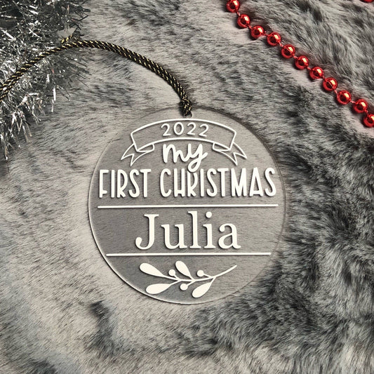 Decorative ornament for 'My First Christmas' with name 'Julia' on a textured surface.