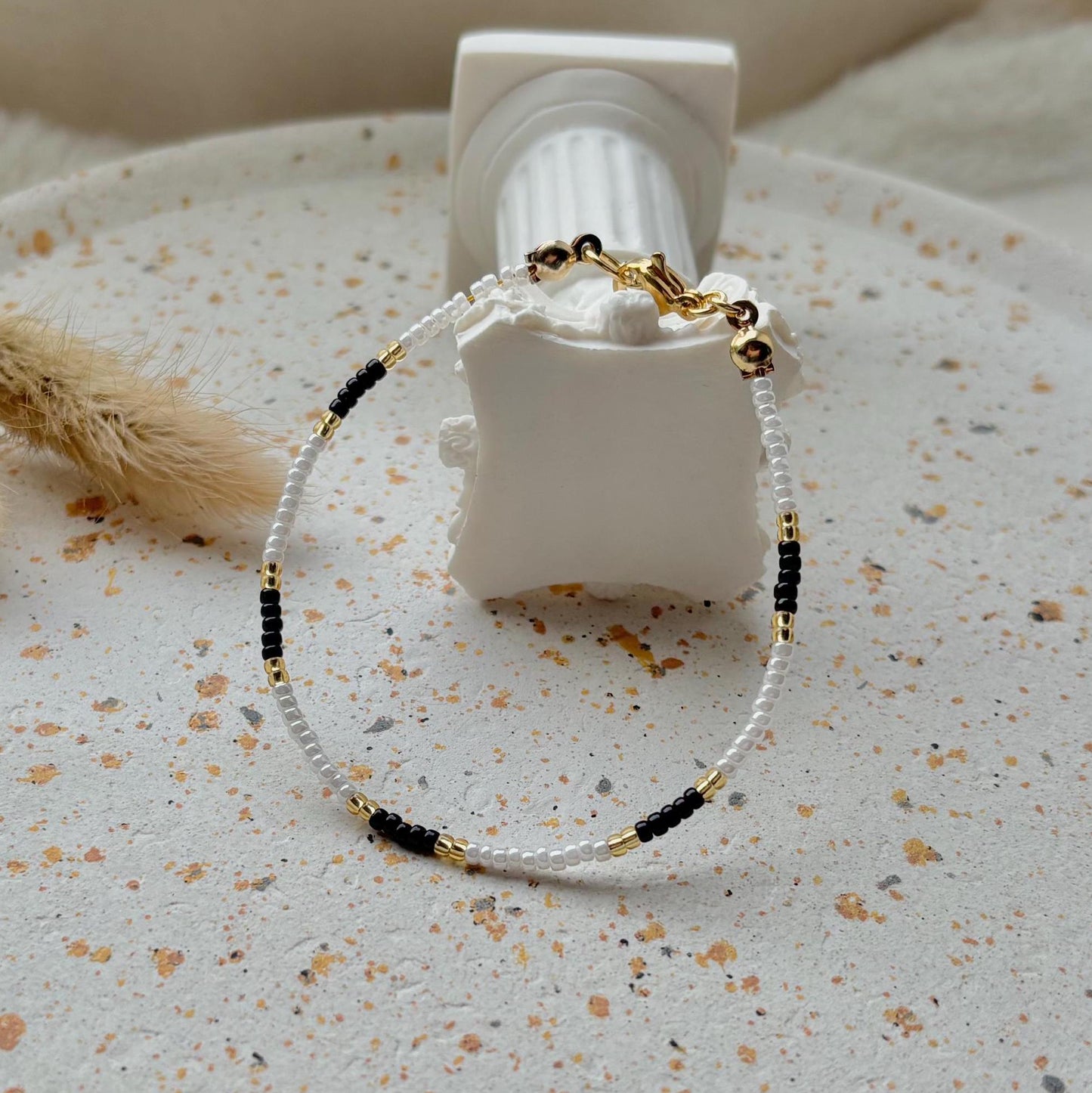 Bracelet with black and gold beads on a textured surface