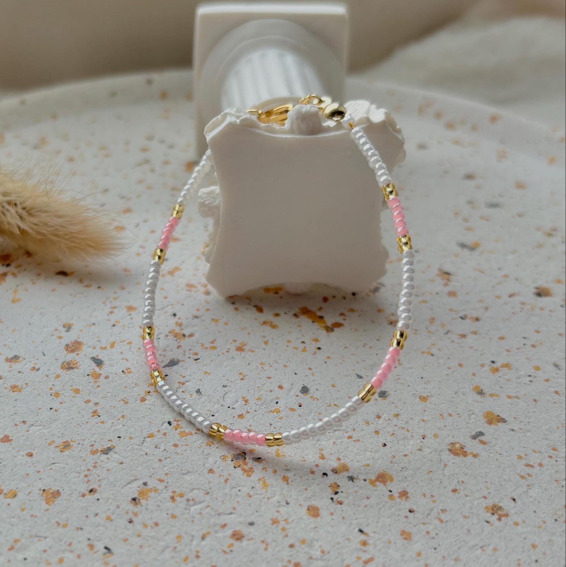 Bracelet with pink and gold beads on a textured surface