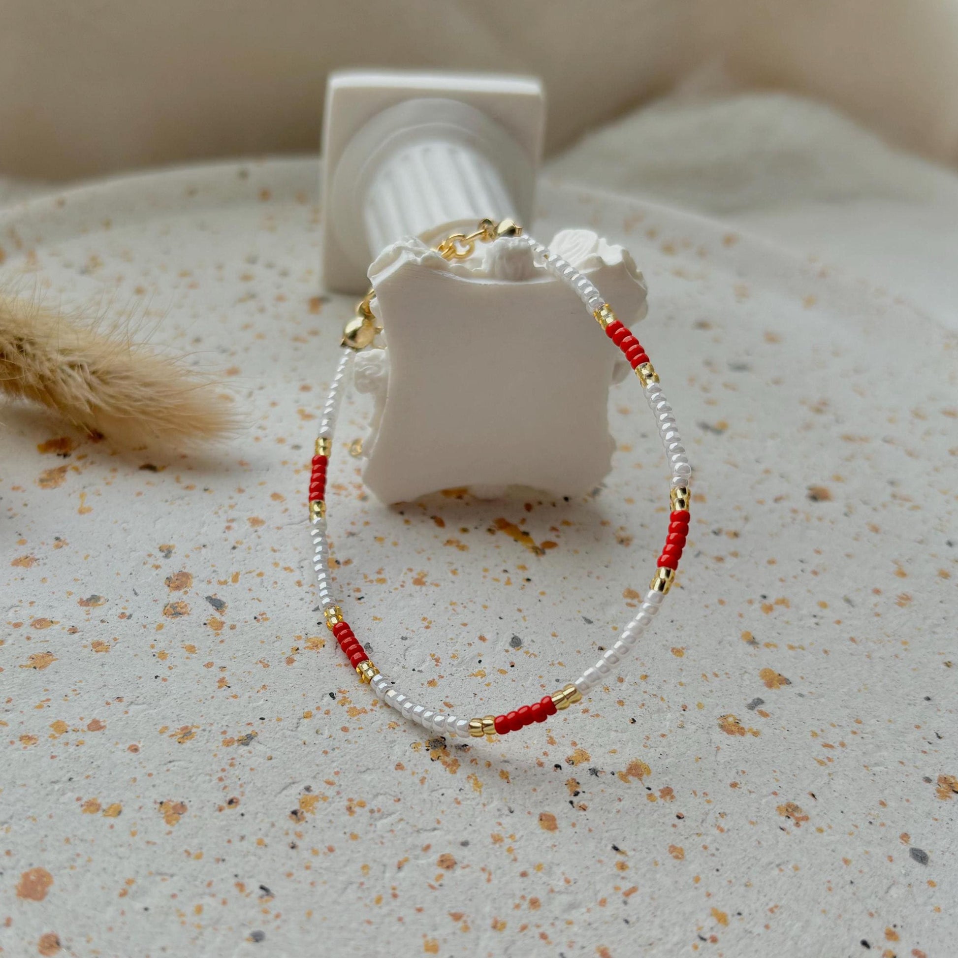 Bracelet with red and gold beads on a textured surface
