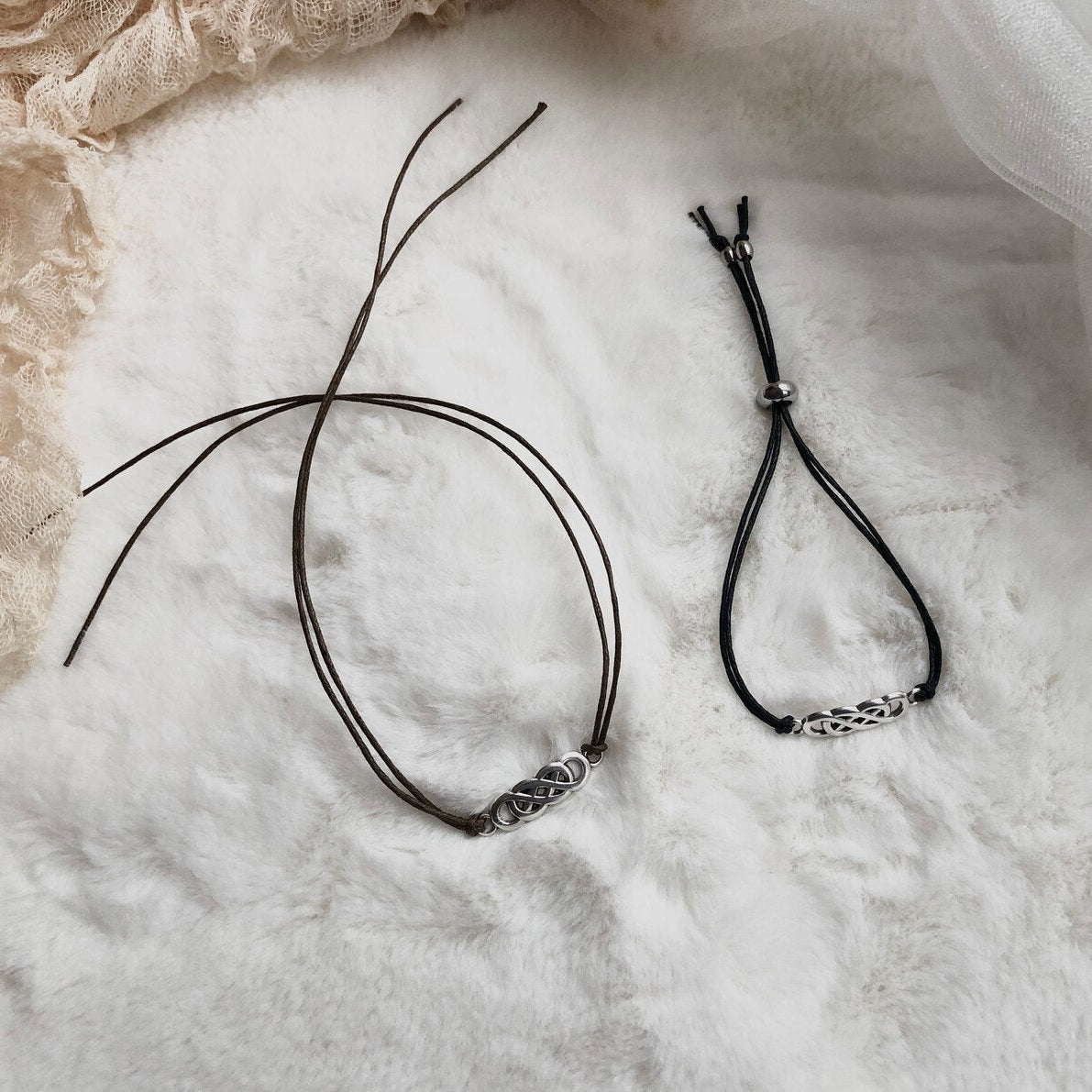 Two black necklaces on a textured white surface