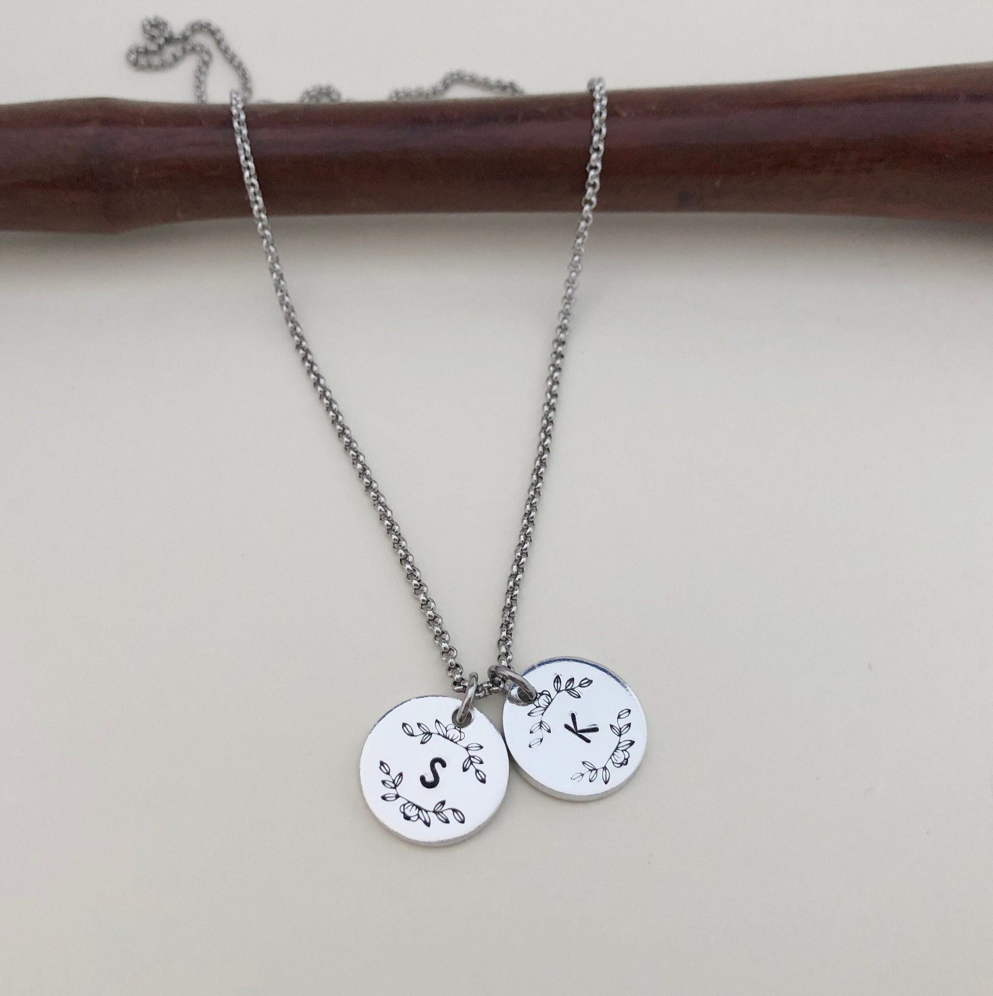 Silver necklace with two round pendants on a plain background