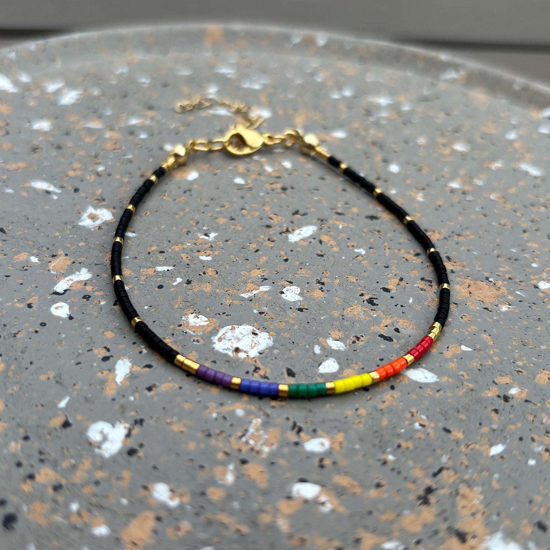 Bracelet with rainbow beads on a speckled surface