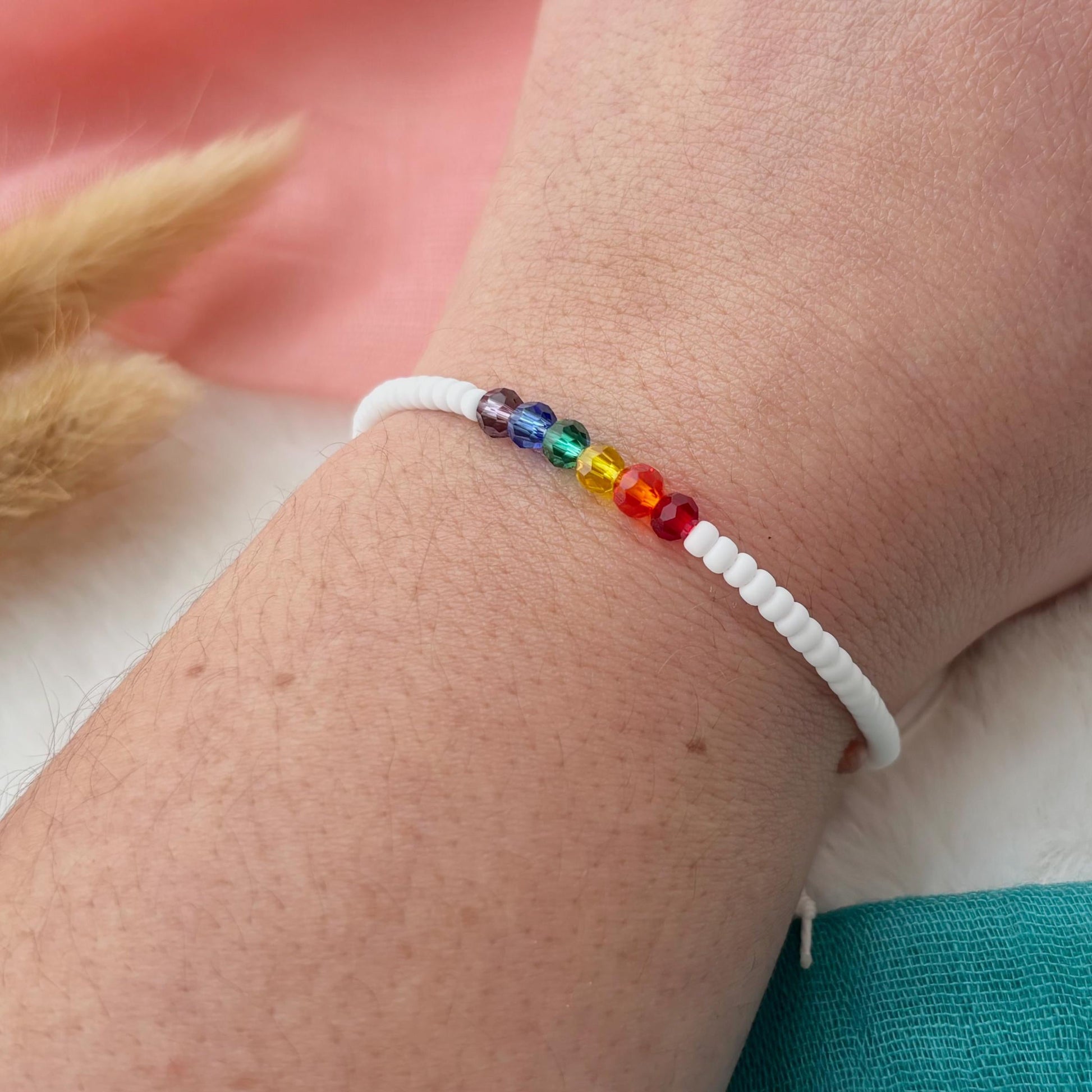 Rainbow beaded bracelet on a wrist with a blurred background