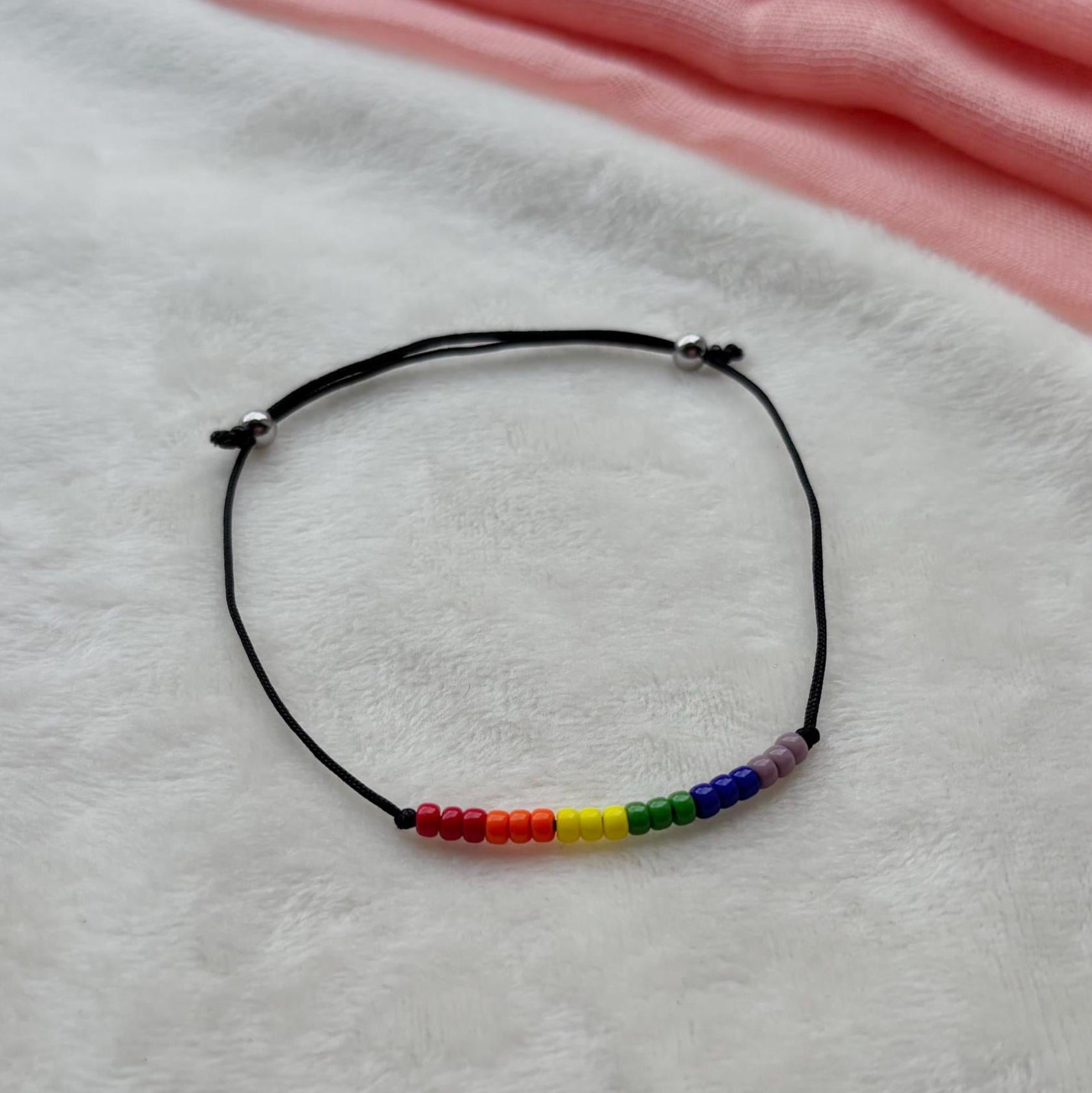 Bracelet with rainbow beads on a white fabric background