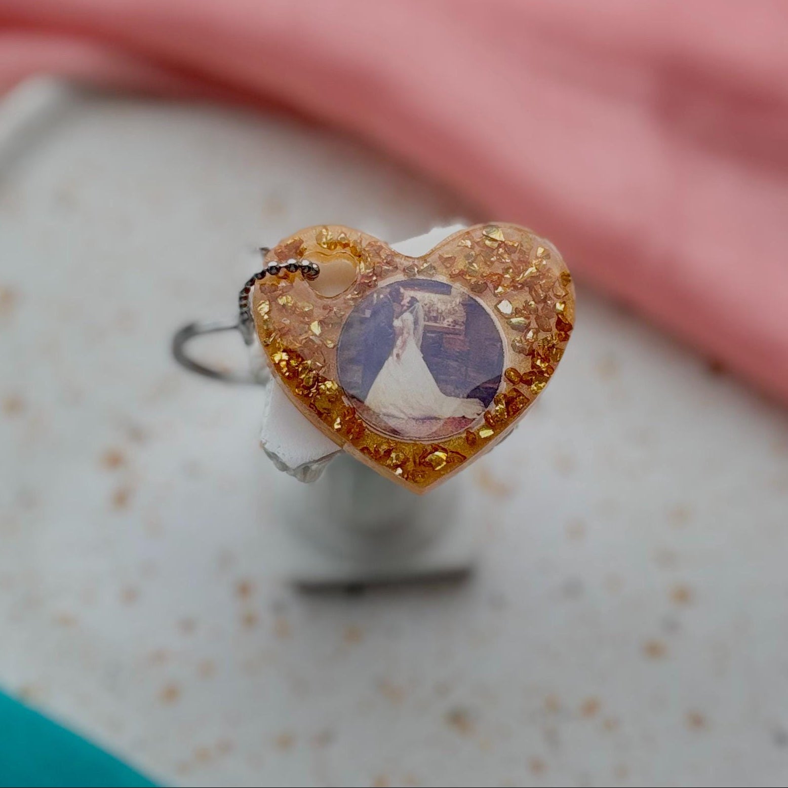 Heart-shaped ring with a colorful stone on a speckled surface