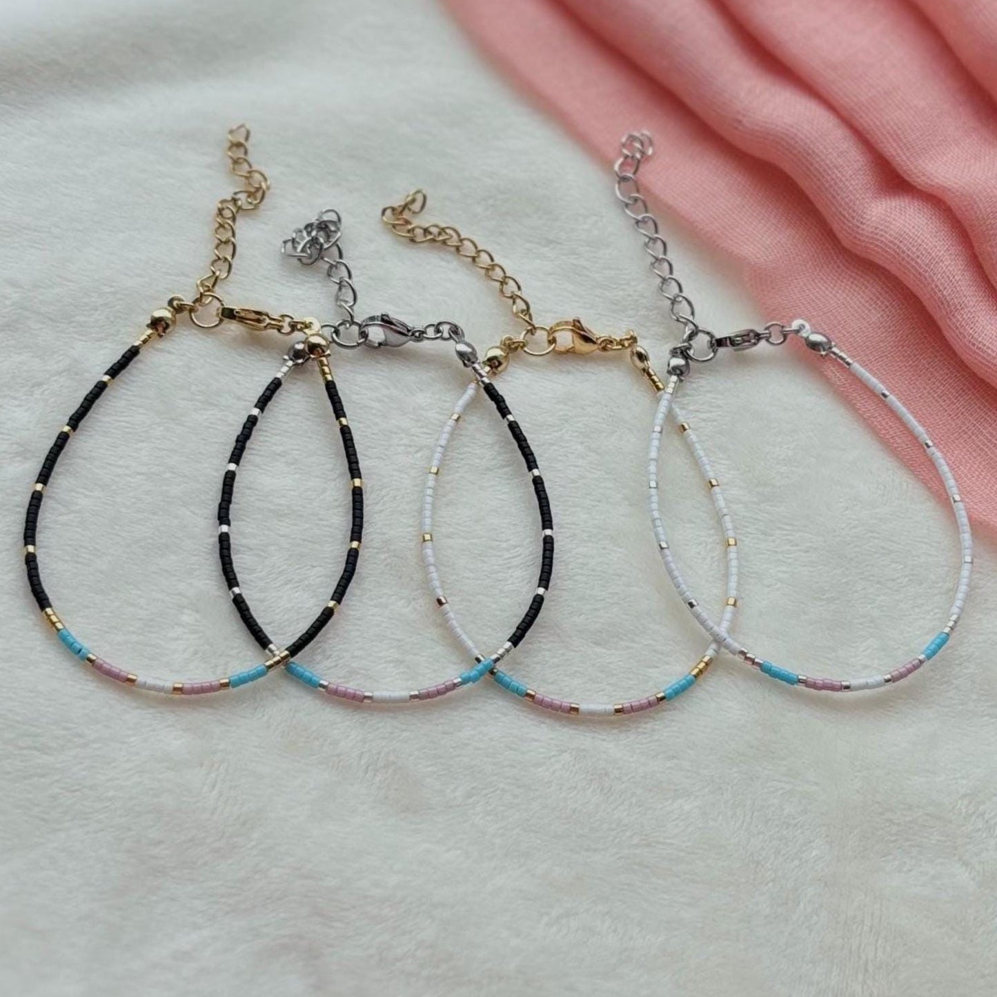 Trans flag bracelets on a light pink fabric background
