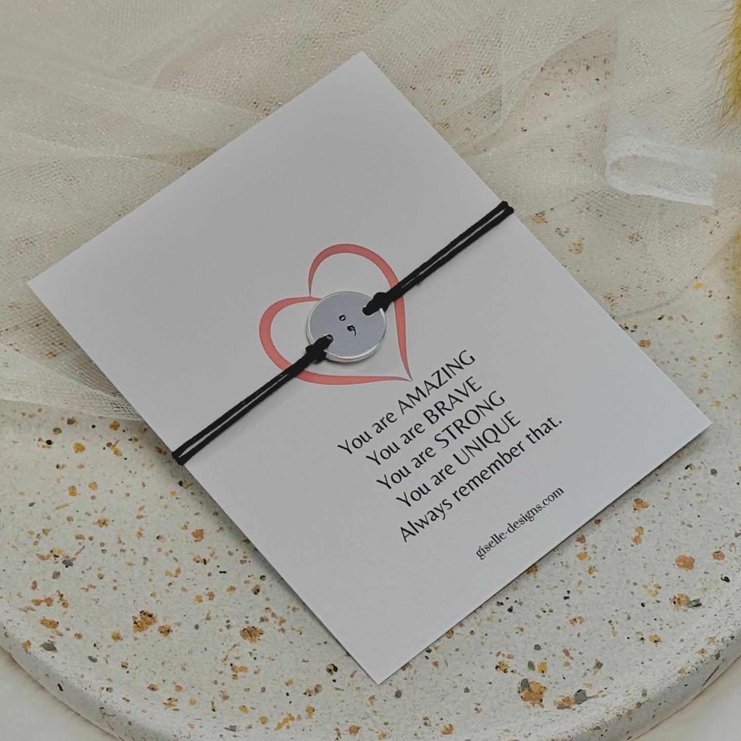 Black bracelet on a card with motivational message on a textured surface