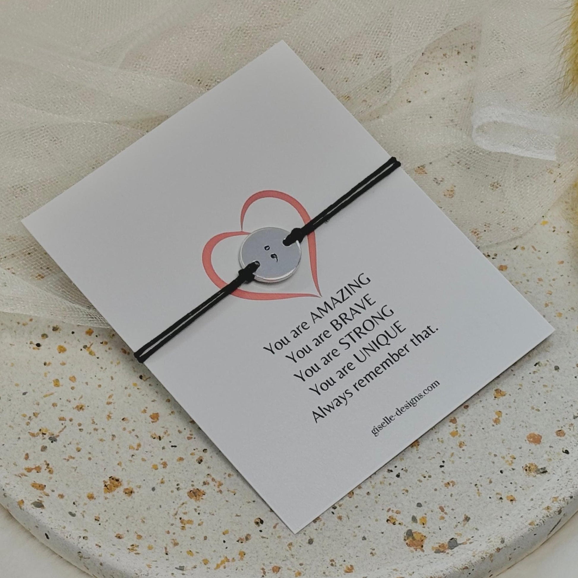 Black bracelet on a card with motivational message on a textured surface